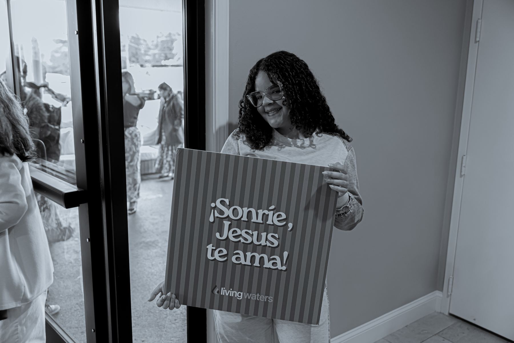 A greeter holding a Sonríe sign, the Spanish version